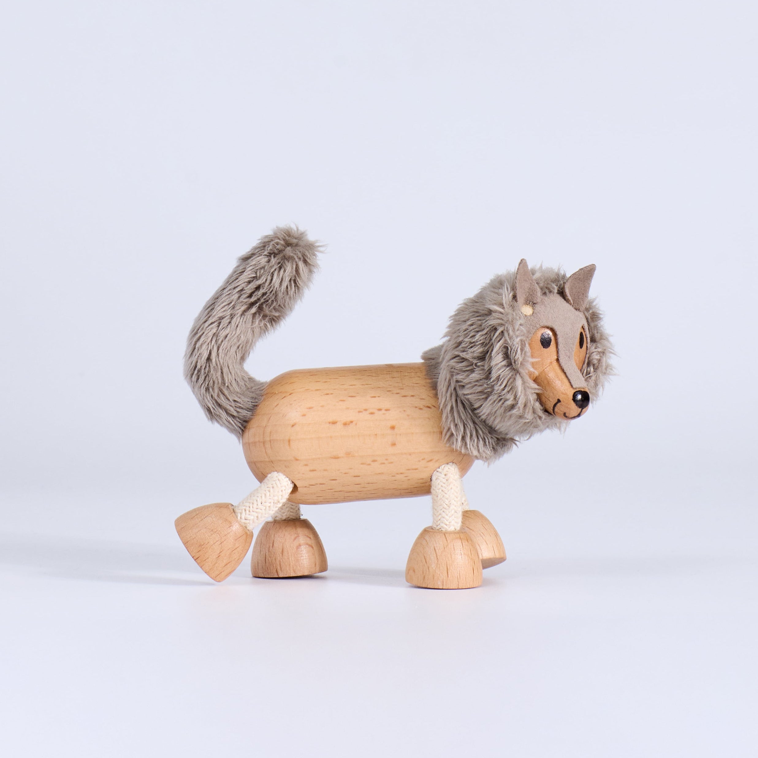 Wooden toy wolf with gray fur on a light gray background